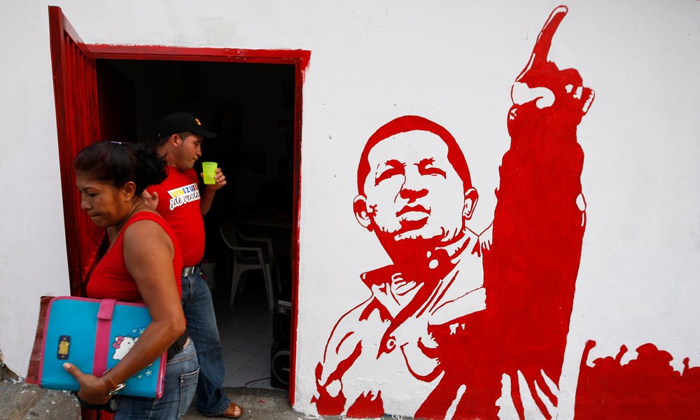 A woman leaves a campaign office of United Socialist Party of Venezuela (PSUV) with a painting of President Hugo Chavez in the neighborhood of Petare in Caracas November 12, 2008. Venezuelans go to the polls on Nov. 23 to elect state governors and city mayors.  REUTERS/Jorge Silva (VENEZUELA)
