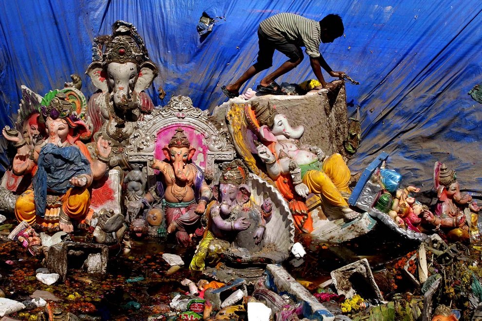 Мальчик ходит среди многоразовых идолов Ганеши на следующий день после фестиваля «Ганеша-чатуртхи», во время которого идолы опускались в воду как символ рождения божества и смывания всех бед человечества, Ахмадабад, Индия. 