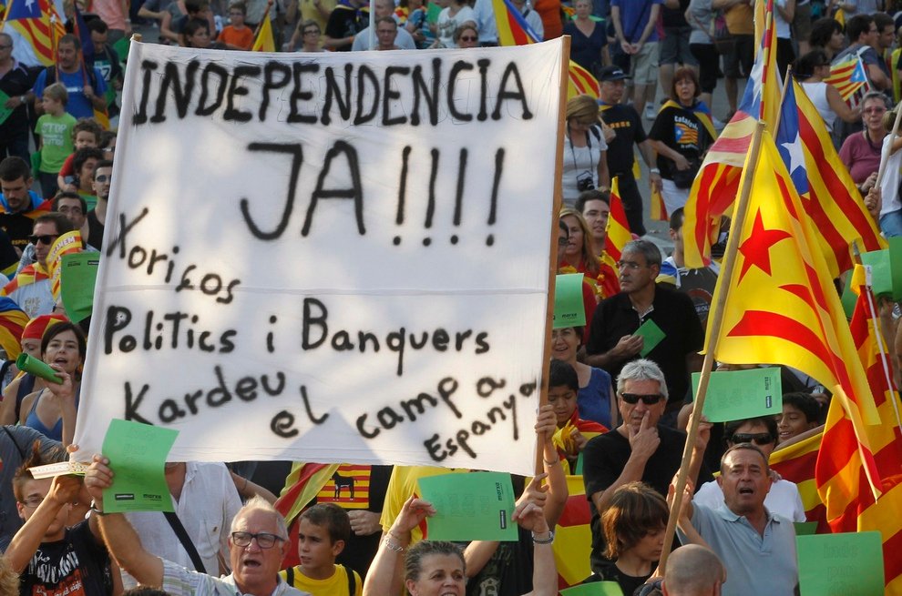 Marchers hold a banner and Catalonian nationalist flags as they demonstrate during Catalan National Day in Barcelona